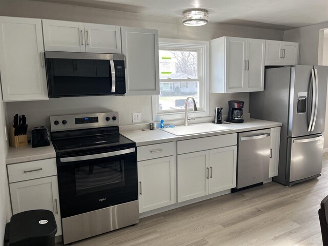 1610 S Oneida St, Green Bay, WI 54304 - kitchen with white cabinets, stainless steel appliances, light countertops, a sink, and light wood-style flooring