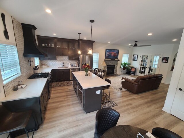 1323 W Lloyd St, Milwaukee, WI 53205 - kitchen featuring a fireplace with flush hearth, light countertops, custom exhaust hood, and appliances with stainless steel finishes