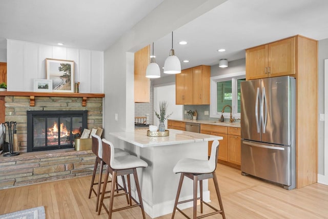 5308 Mckenna Rd, Monona, WI 53716 - kitchen featuring stainless steel appliances, a breakfast bar, light wood-style flooring, a fireplace, and backsplash