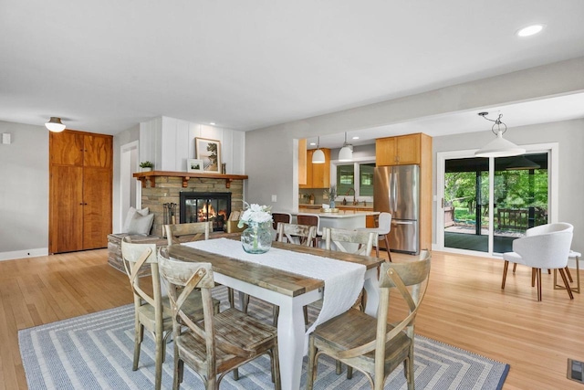 5308 Mckenna Rd, Monona, WI 53716 - dining room featuring light wood-style floors, a glass covered fireplace, and baseboards