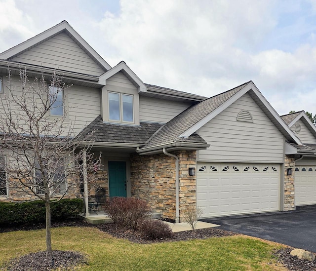 view of front facade with a garage, driveway, stone siding, and a front yard