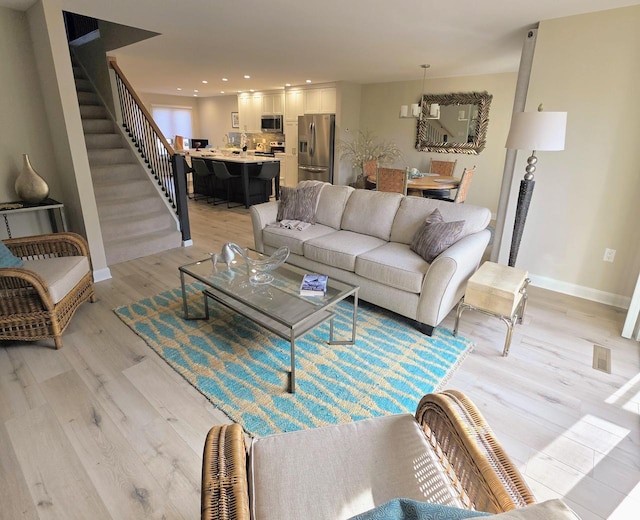 living area featuring stairway, baseboards, light wood-style floors, and recessed lighting