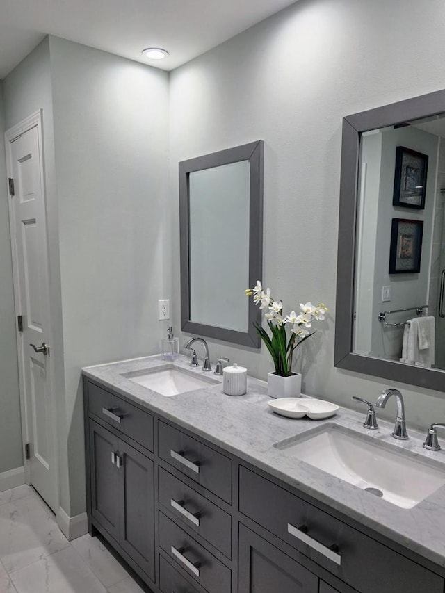 full bath featuring double vanity, marble finish floor, and a sink