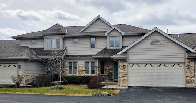 view of front of home with driveway, stone siding, and a garage