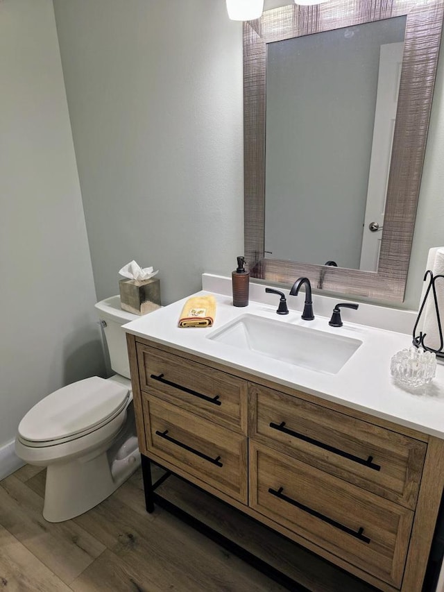 bathroom with wood finished floors, vanity, and toilet