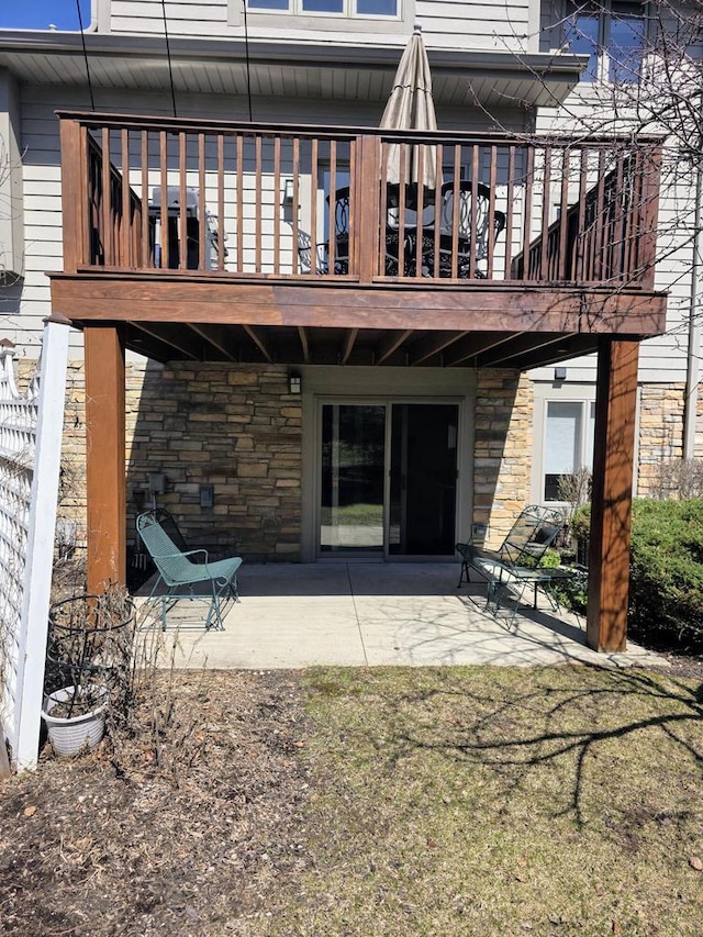 back of house featuring stone siding and a patio area