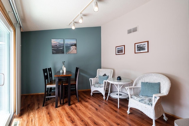 dining area with baseboards, visible vents, wood finished floors, and rail lighting