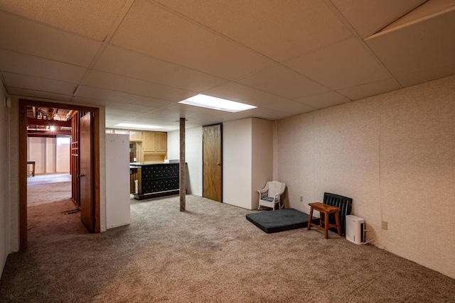 finished basement with carpet and a paneled ceiling