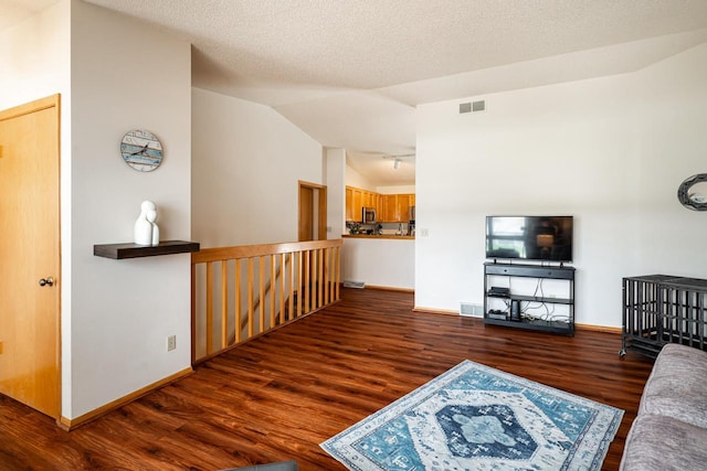 living room featuring lofted ceiling, wood finished floors, visible vents, and baseboards