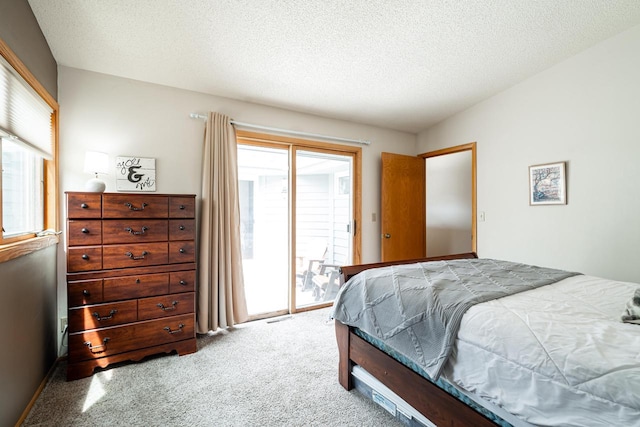 carpeted bedroom with visible vents, access to exterior, a textured ceiling, and multiple windows
