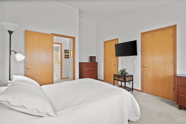 bedroom with ensuite bath and light colored carpet