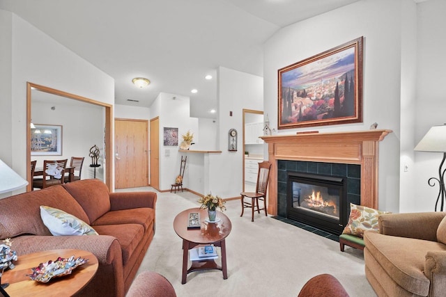 living room featuring recessed lighting, lofted ceiling, a tile fireplace, and carpet flooring