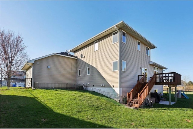 back of property with a lawn, fence, stairway, and a deck