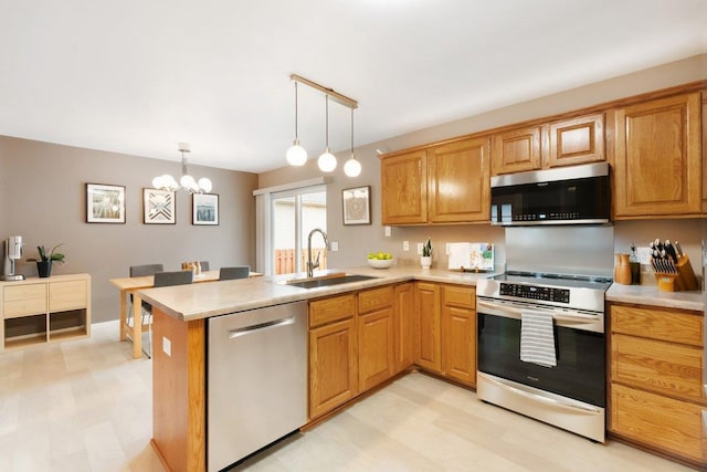 kitchen with light countertops, a sink, pendant lighting, a peninsula, and appliances with stainless steel finishes