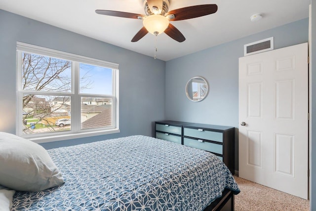 carpeted bedroom featuring a ceiling fan and visible vents