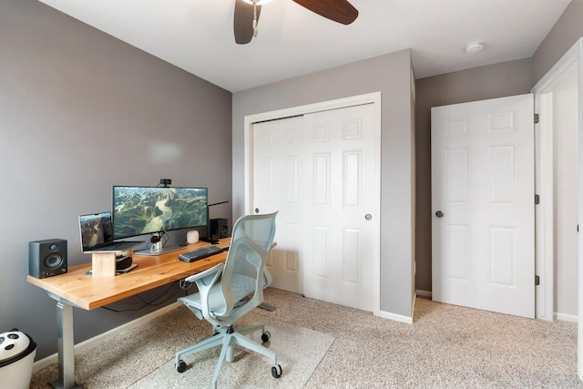 carpeted office space with baseboards and a ceiling fan