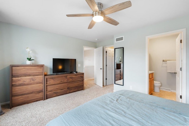 bedroom with a ceiling fan, ensuite bathroom, light carpet, baseboards, and visible vents