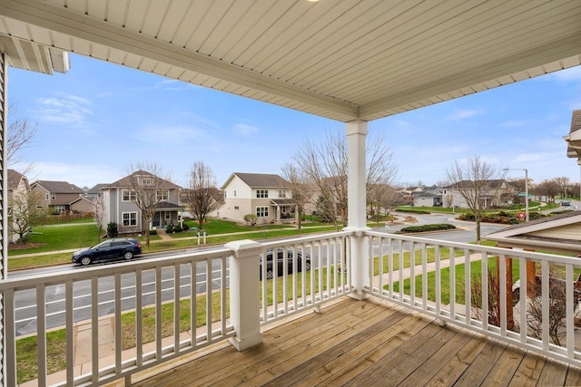 wooden terrace featuring covered porch, a yard, and a residential view