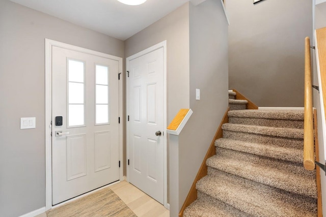 entryway featuring baseboards, stairs, and light wood-style flooring