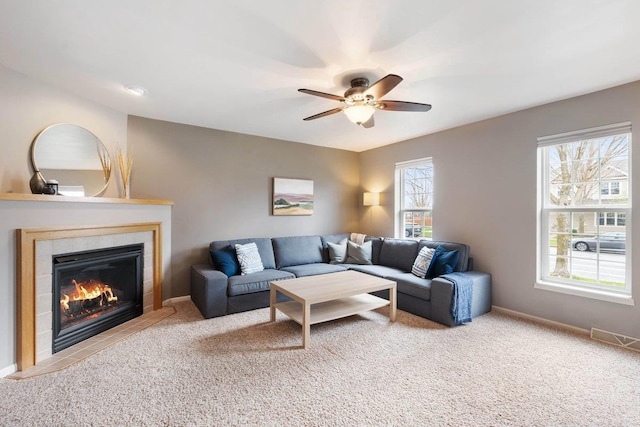 carpeted living area with a tile fireplace, visible vents, baseboards, and ceiling fan