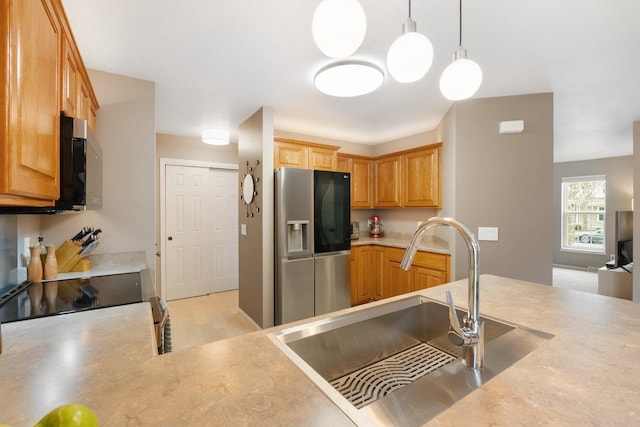 kitchen featuring light countertops, decorative light fixtures, appliances with stainless steel finishes, and a sink