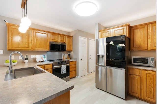 kitchen featuring a toaster, light countertops, a sink, hanging light fixtures, and appliances with stainless steel finishes