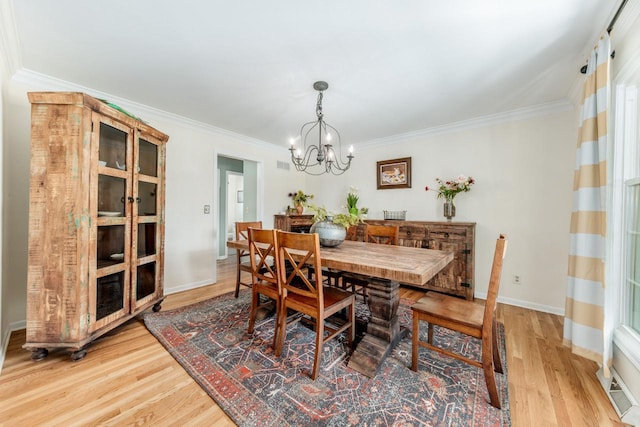 dining room featuring light wood-style flooring, crown molding, baseboards, and an inviting chandelier
