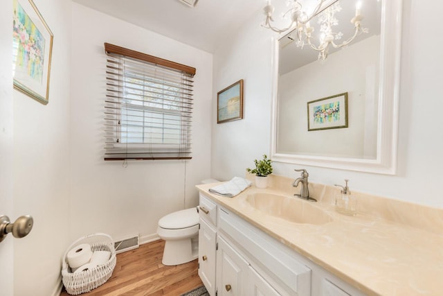 bathroom featuring wood finished floors, visible vents, toilet, vanity, and a chandelier