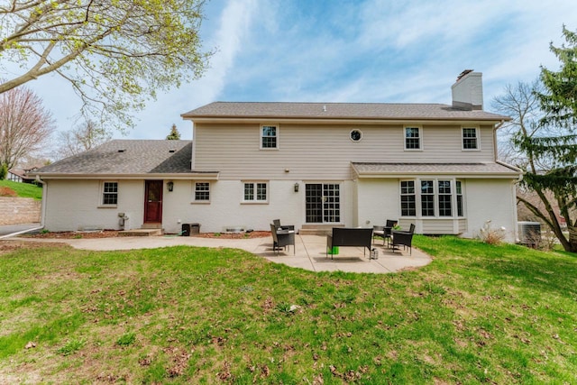 rear view of house with brick siding, a lawn, a patio, and a chimney