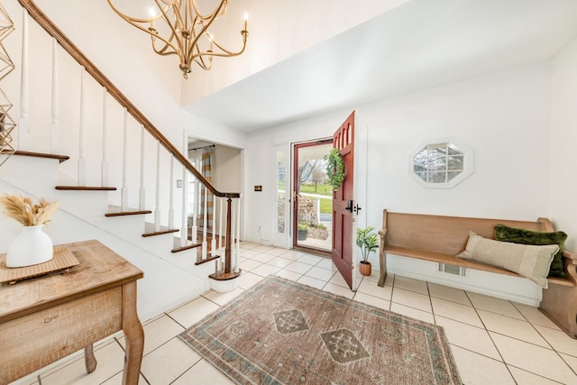 entryway featuring tile patterned flooring, a towering ceiling, an inviting chandelier, visible vents, and stairs