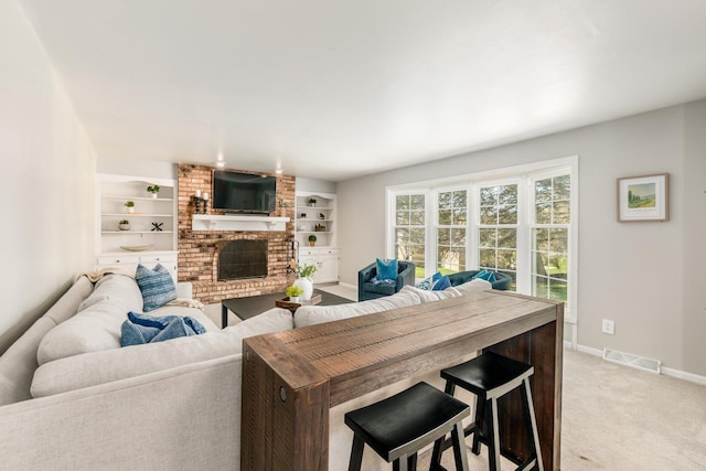 living area with built in shelves, light colored carpet, baseboards, a brick fireplace, and visible vents