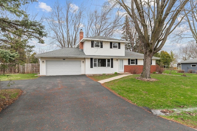 traditional-style house with a chimney, a front lawn, aphalt driveway, an attached garage, and fence