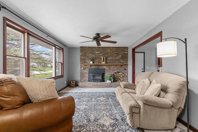 living room with a ceiling fan, baseboards, and a wood stove