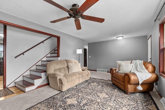 living area with stairway, visible vents, a ceiling fan, and baseboards