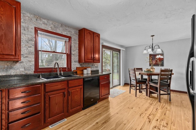 kitchen with light wood finished floors, a sink, dark countertops, visible vents, and black appliances