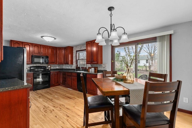 kitchen with black appliances, decorative backsplash, dark countertops, and a chandelier