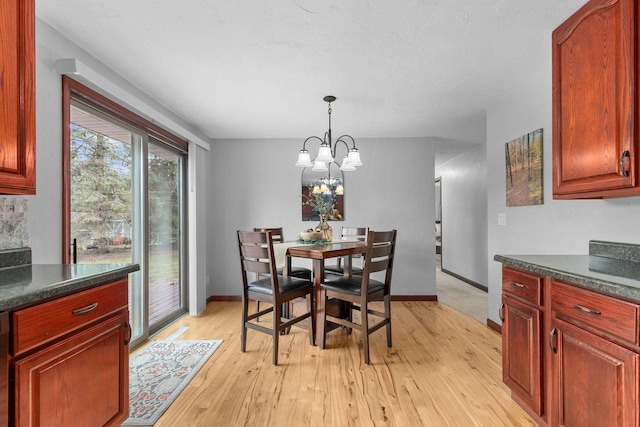 dining space featuring baseboards, an inviting chandelier, and light wood-type flooring