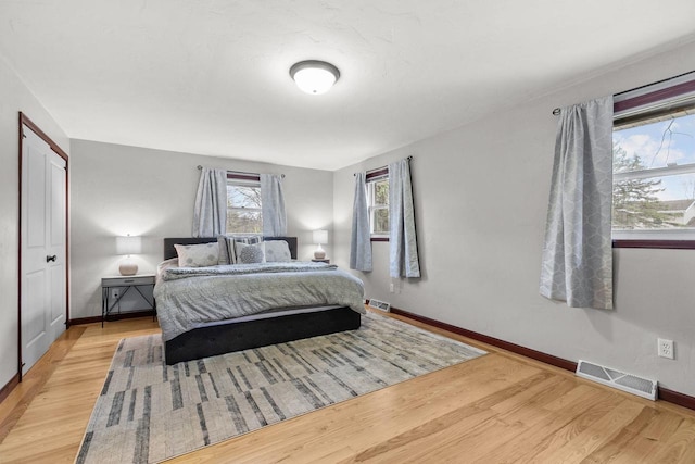 bedroom featuring baseboards, light wood finished floors, and visible vents