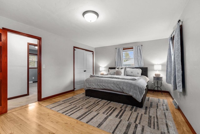 bedroom featuring visible vents, baseboards, wood finished floors, and a closet