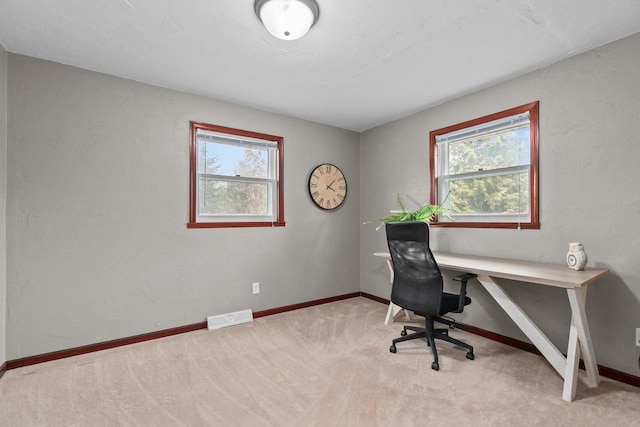 carpeted office space featuring baseboards, visible vents, and plenty of natural light