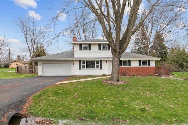 traditional-style home with a chimney, fence, an attached garage, driveway, and a front yard