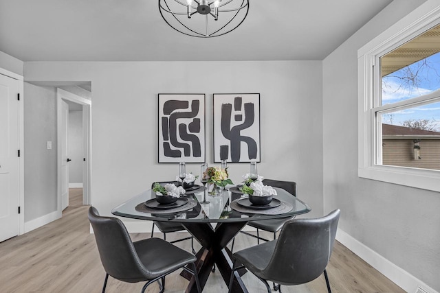 dining room with light wood-style flooring, baseboards, and an inviting chandelier