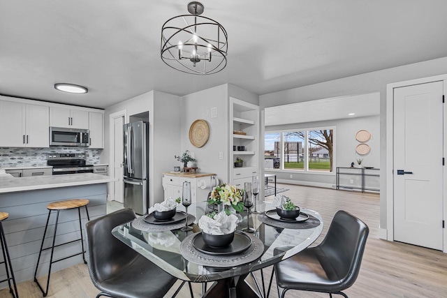 dining area featuring a notable chandelier and light wood-style flooring