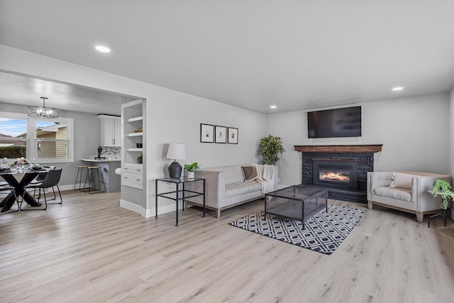 living area featuring a glass covered fireplace, wood finished floors, and recessed lighting