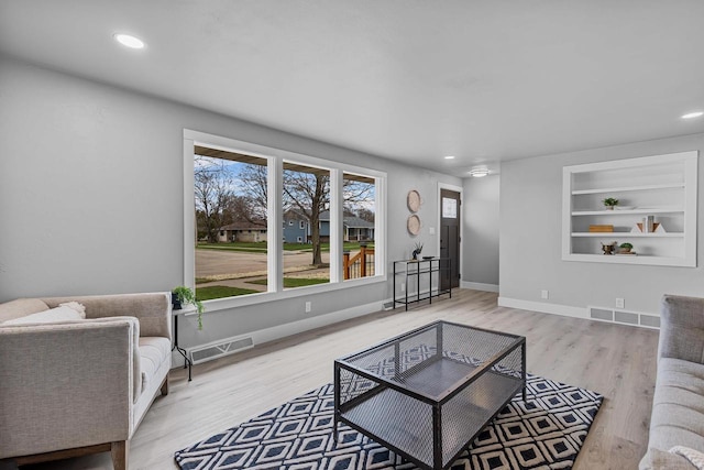 living area featuring a healthy amount of sunlight, wood finished floors, and visible vents