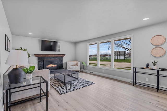 living area featuring recessed lighting, wood finished floors, visible vents, baseboards, and a glass covered fireplace