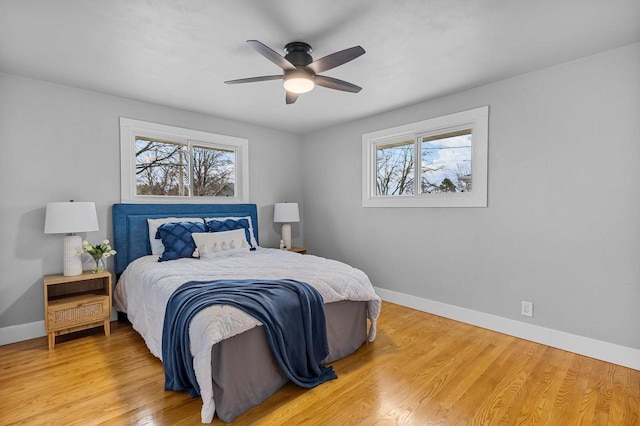 bedroom featuring wood finished floors, baseboards, ceiling fan, and multiple windows