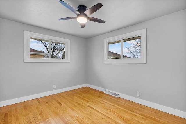 spare room with baseboards, light wood-style flooring, visible vents, and a ceiling fan