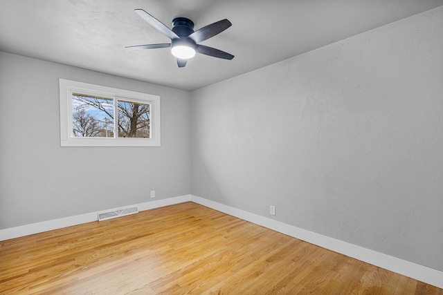 spare room featuring wood finished floors, visible vents, baseboards, and ceiling fan