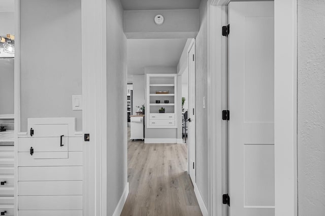 corridor featuring light wood-style flooring and baseboards